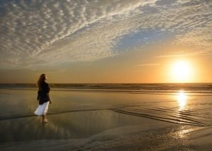 Walking on beach at sunrise looking at sky