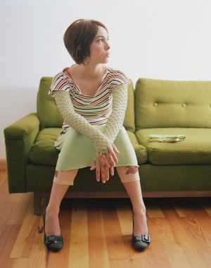 Youth sits on sofa, looking away from camera