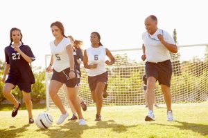 Teen girls playing soccer on field