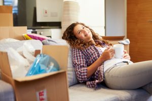 Woman takes break from moving and relaxes on sofa with warm drink 