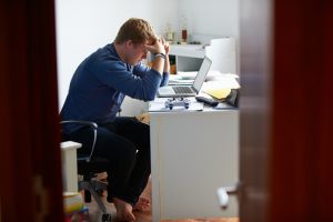 Distance shot of person with head in hands, seemingly frustrated with work