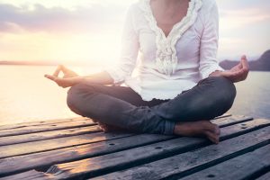 Woman meditating at sunset on boardwalk