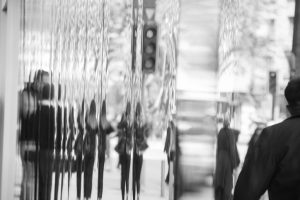 Black and white photo of blurred reflections of passersby 