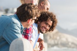 four young adults look out over water smiling and talking