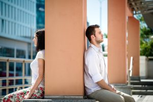 Couple sits on either side of pillar, backs to each other