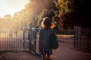 A person stands with back to camera looking at open gate