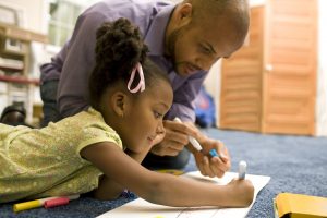 Little girl coloring with father