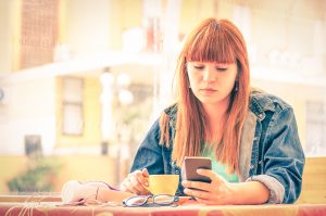 Person drinking coffee and looking at phone