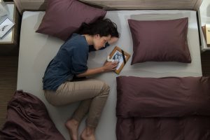 Woman lying in bed with photo of husband