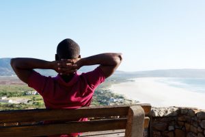 Athletic person sits on bench with hands behind head and looks out over city and lake