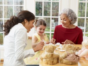 Little girl has tea party at table with mother and grandmother