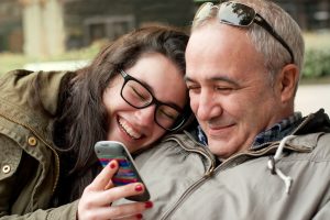 father and teen looking at phone