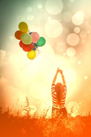 letting go of colorful balloons in a field