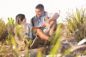 child and parent hiking and reading a book