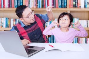 Elementary school child has fingers in ears at library table while parent tries to get child's attention