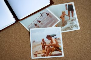 Open journal and three photos of a family at the beach lie on table