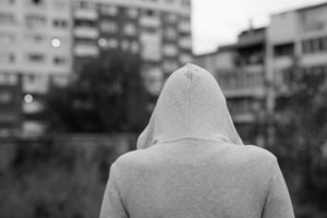 Grayscale photo of person in hoodie looking out toward city