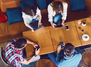 Overhead view of small group of young adults networking at cafe table
