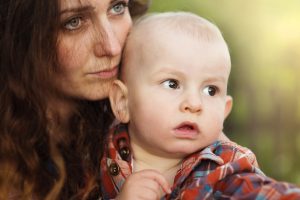 Sad mother holding baby outside