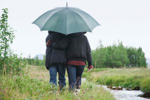 Couple walking together under umbrella by stream