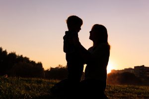 Side view of silhouette of mother kneeling down, holding son's shoulders