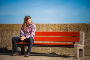 wearing plaid shirt casual style relaxing outdoor at summer sunny windy day sitting on bench