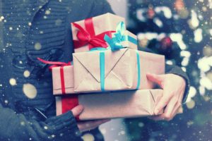 Close view of a person in a coat holding a stack of wrapped gifts