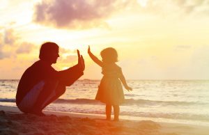 Child gives father a high-five at the beach