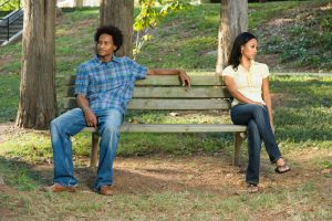 Couple sit on opposite ends of bench, looking away from each other