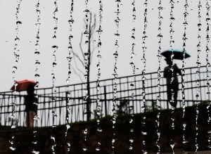 Two people with umbrellas in the rain stand apart looking back toward each other