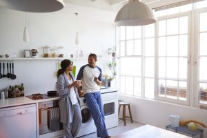 Shot of a young couple talking and drinking coffee in a spacious white kitchen