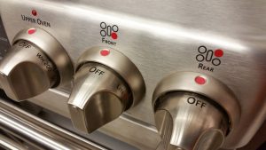 Close-up photo of three chrome knobs that control the range of a gas stove