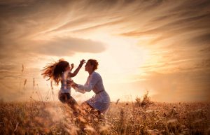 Sepia-toned image capturing motion of child running up to parent and leaping into parent's arms