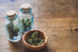 Two small glass jars and small clay dish hold marijuana