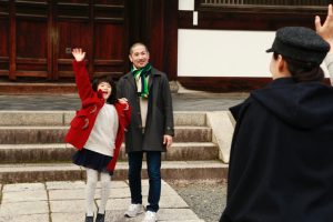 Man holds little girl's hand as she waves to her mother who has come to pick her up