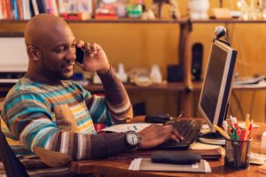 Content man uses cell phone at desk in home office