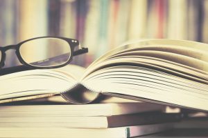 Glasses perched on stack of open books