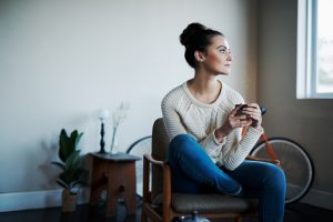 Woman holding mug while looking out window