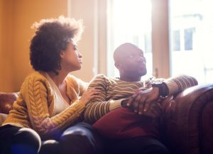 Person in jeans and yellow cardigan leans in toward partner who is looking the other direction, apparently disinterested in resolving conflict