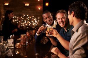Diverse group of men at fancy bar with wood counters and soft lights