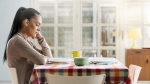 Person with long hair tied into ponytail sits and waits at table alone