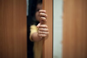 child hiding behind door