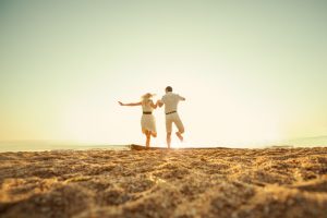Distance rear view of couple holding hands and jumping together on one foot each
