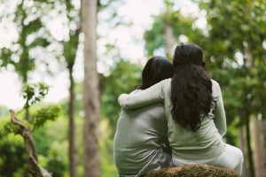 Rear view of hugging female friends sitting in the park