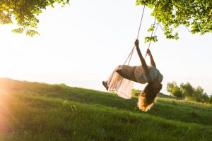 Distance photo shot of person swinging with head tilted back and hair hanging down