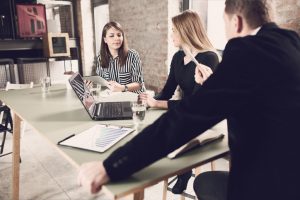 Angry manager and assistant look to employee for explanation during meeting in office room