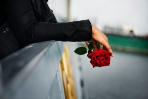 Person in black coat holding rose