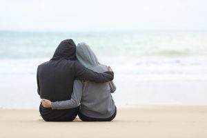 Two people hugging while sitting on beach
