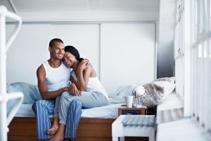 Shot of a happy young couple sitting on their bed in pajamas