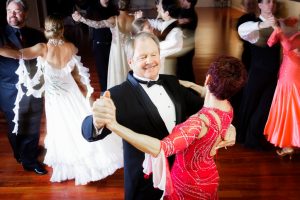 Overlooking view of several couples dancing in ballroom with hardwood floors